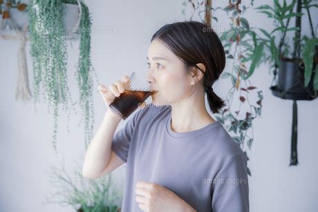 明るい植物のある室内でドリンクを飲む日本人女性の写真素材 FYI05119833 ストックフォトの Qlean Market