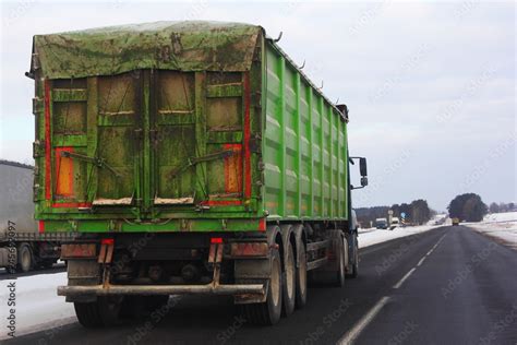 Heavy semi trailer truck with tented green open top container on winter ...