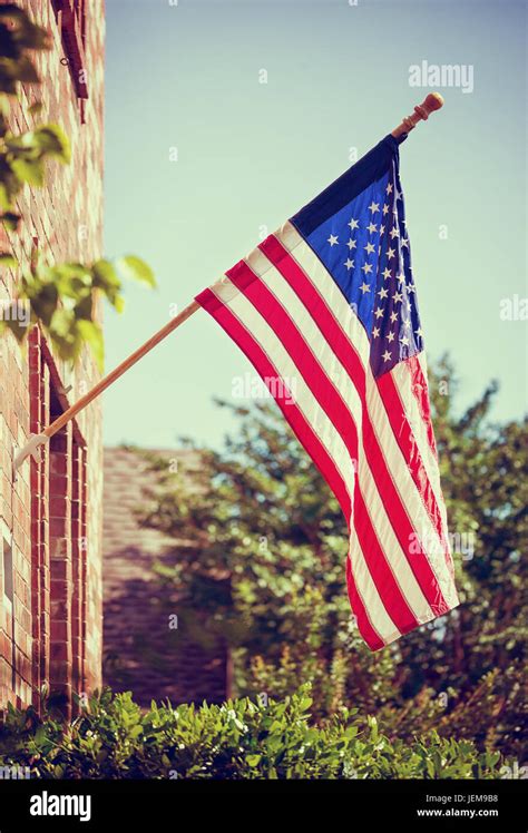 Patriotic American Flag Hanging In Front Of A Home Blue Sky With Copy