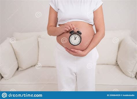 A Pregnant Woman With A Naked Belly Holds An Alarm Clock Intended Date Of Birth Stock Image