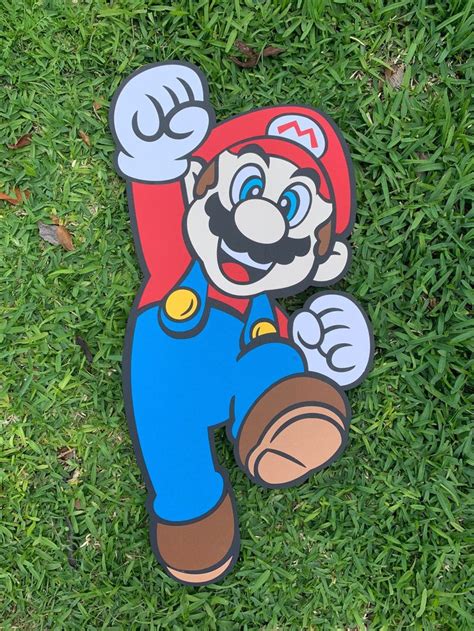 A Paper Cut Out Of Mario Is Laying On The Grass With His Arms In The Air