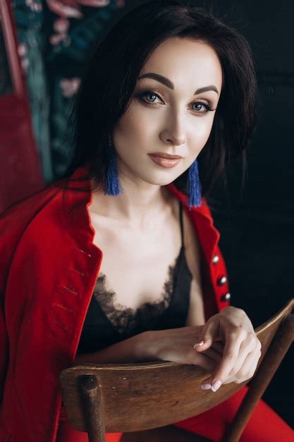 Free Photo Attractive Brunette In Red Suit Sits On The Old Chair In Dark Studio