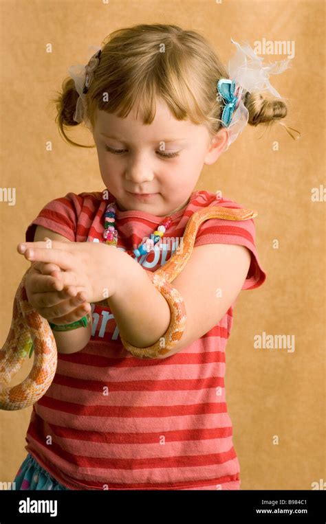 Studio Portrait Of Young Blond Girl Holding Pet Corn Snaketan Backdrop