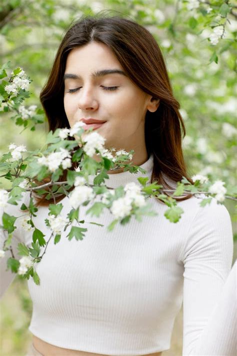 Attractive Model Having Photoshoot In Blooming Garden Smelling Tree