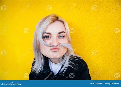 Portrait De La Belle Fille Blonde Dans Une Veste Noire Et Souriante Tenant Ses Cheveux Comme