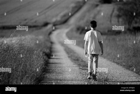 Boy Goes Away Teenage Boy With Backpack Walking Away On The Rural Road