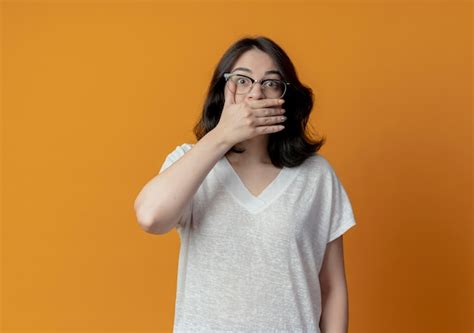 Sorprendido joven bastante caucásica con gafas poniendo la mano en la