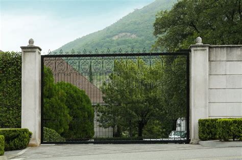 Beautiful Stone Fence With Ornate Black Metal Gates Around House And