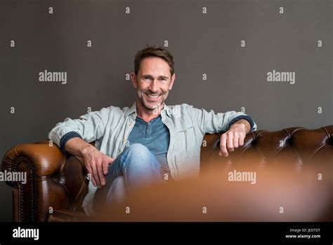Portrait Of Smiling Mature Man Sitting On Leather Couch Stock Photo Alamy