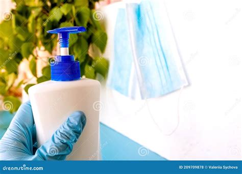 A Hand In A Medical Glove Holds A Bottle With An Antiseptic On A