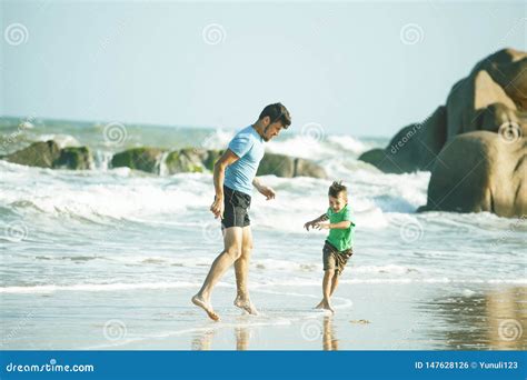 Familia Feliz En La Playa Que Juega Padre Con La Costa De Mar Del Hijo