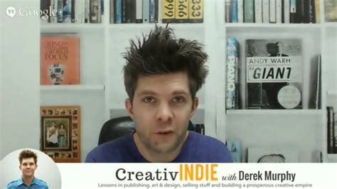 A Man Sitting In Front Of A Book Shelf With Books On The Wall Behind Him