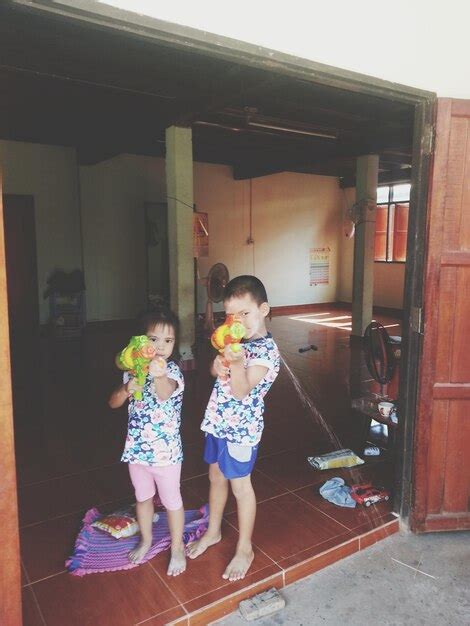 Premium Photo Portrait Of Siblings Playing With Squirt Guns While