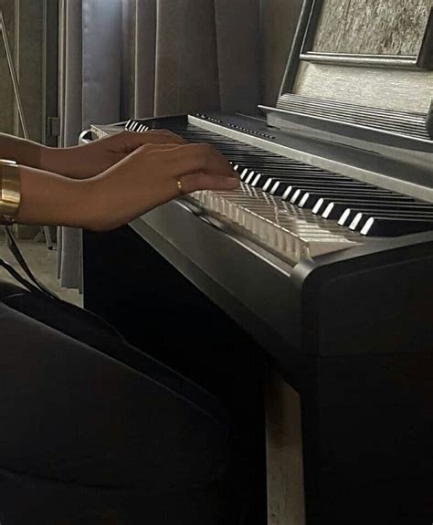 A Woman Is Sitting At A Piano Playing The Music On Her Hand And Holding