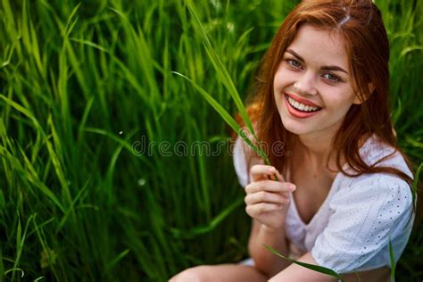 Portrait Of A Happy Laughing Woman Sitting In Tall Grass In A Field