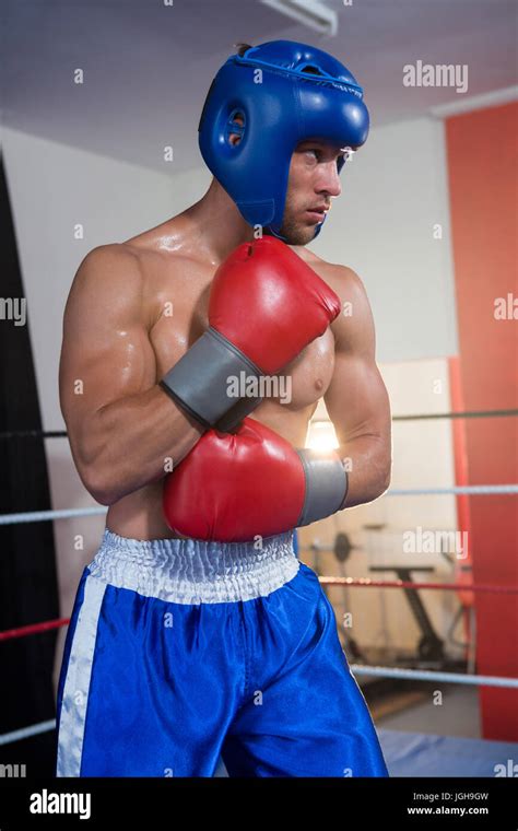 Young Male Boxer Wearing Blue Headgear Standing In Boxing Ring Stock