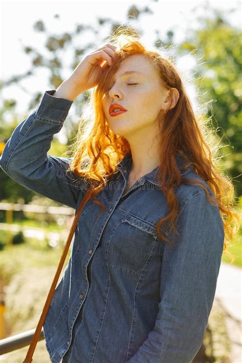 Menina De Cabelo Vermelha Sensual Nos Vidros Que Levantam Nos Raios Do