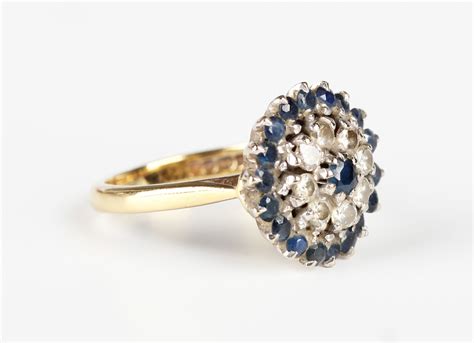 An 18ct gold, sapphire and diamond cluster ring, claw set with a ...