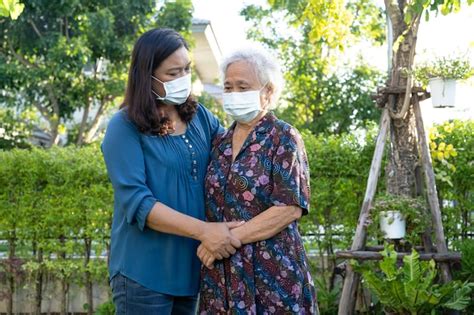 El cuidador ayuda a una anciana asiática mientras camina feliz en el