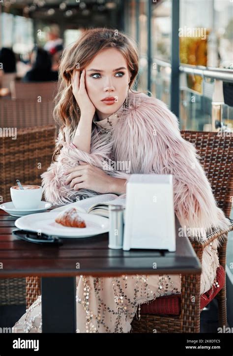 Beautiful Girl Sitting In Restaurant Drinking Coffee Cappuccino And Reading A Book Portrait