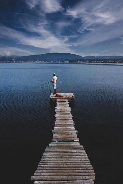 Premium Photo Man Standing On Pier Over Lake Against Sky