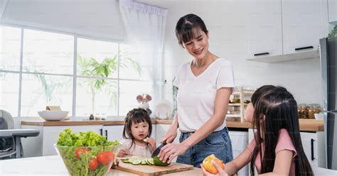 두 어린 딸과 함께 야채 샐러드를 요리하는 아시아의 아름다운 어머니 행복한 가족 매력적인 돌보는 부모 엄마는 집에서 부엌에서