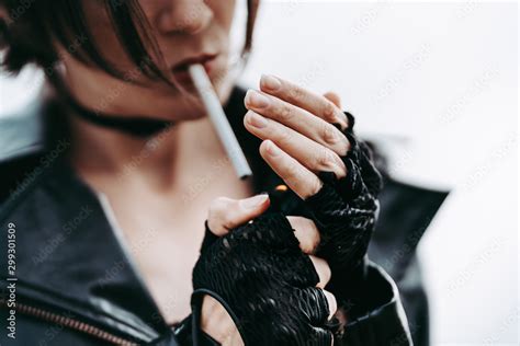 Cool Rock girl in a black leather jacket and gloves lights a cigarette ...