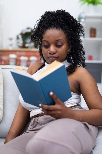 Premium Photo Young Woman Reading Book While Sitting On Sofa At Home