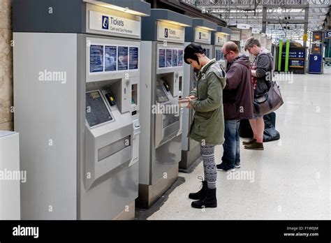 Los pasajeros comprar billetes de tren en una máquina de billetes automática en la plataforma ...