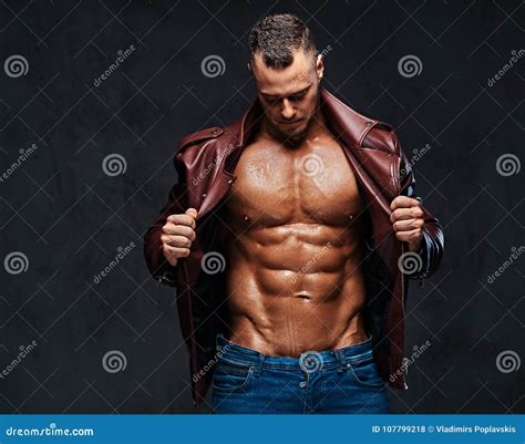 O Homem Muscular Vestiu Se Em Um Revestimento E Em Cal As De Brim Foto