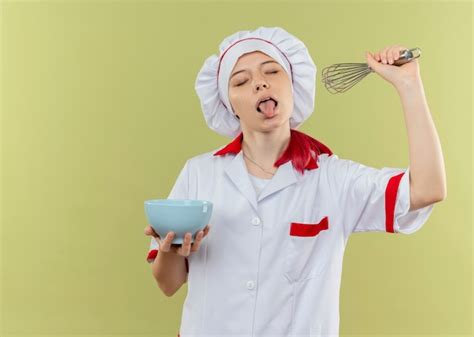 Jeune femme blonde joyeuse chef en uniforme de chef coince la langue avec les yeux fermés