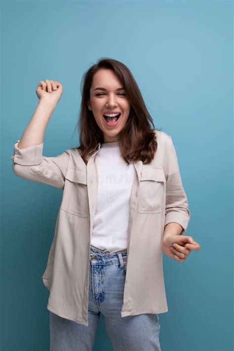 Brunette Positiva Joven Dama De La Morena Vestida Con Una Camisa Y Jeans Muestra Con La Mano Que