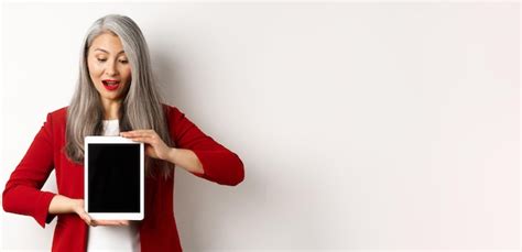 Dame de bureau asiatique mature d affaires montrant l écran de la tablette numérique et