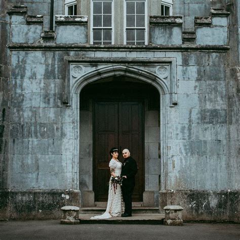 a bride and groom standing in front of an old building