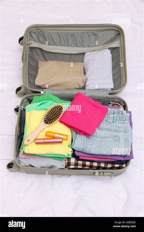 Open Grey Suitcase With Clothing On Bed Stock Photo Alamy