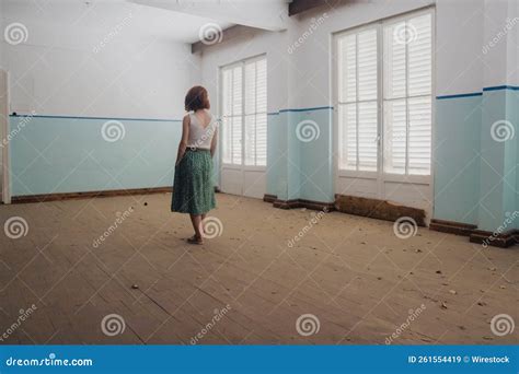 Girl Standing In An Abandoned Empty House With Big Windows And Fallen