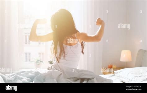 Beautiful Brunette Is Waking Up In The Morning Stretches In The Bed Sun Shines On Her From The