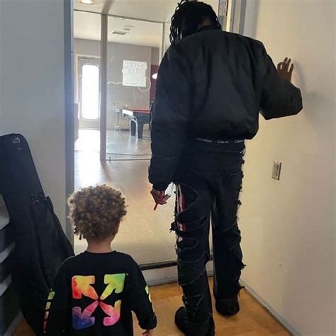 a man standing next to a little boy in front of a door with a guitar case