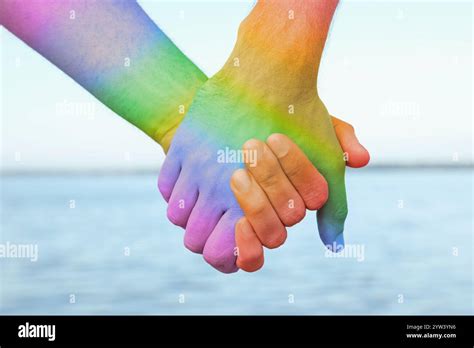 Gay Couple Holding Hands Near River Closeup Toned In LGBT Colors Tolerance And Acceptance