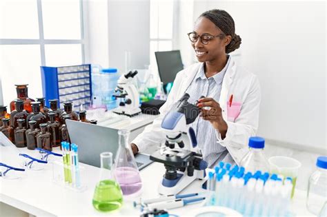 African American Woman Scientist Using Laptop And Microscope At