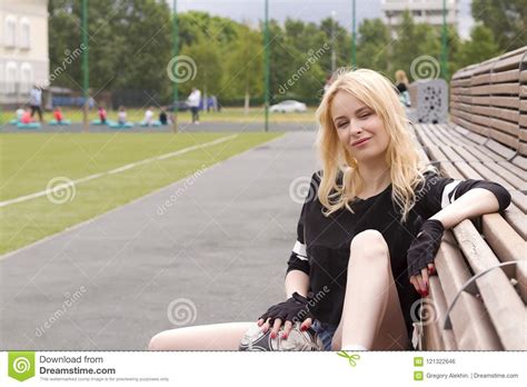 A Menina Senta Se No Banco No Campo De Futebol A Bola Foto De Stock