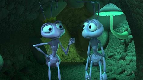 Two Bugs Standing Next To Each Other In Front Of A Green Cave With