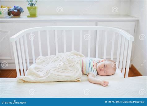 Baby Sleeping In Co Sleeper Crib Attached To Parents` Bed Stock Photo