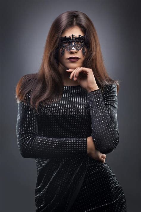 Beautiful Woman With Black Lace Mask Over Her Eyes On The Dark Gray