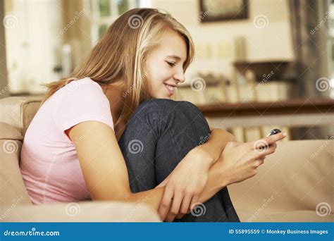 Adolescente Que Senta Se No Telefone Celular De Sofa At Home Texting On