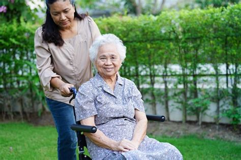 El cuidador ayuda a una anciana asiática con discapacidad a una