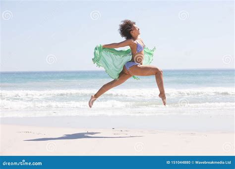 Frau Im Bikini Mit Dem Schal Der Auf Den Strand Springt Stockfoto Bild Von Lebensstil