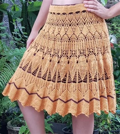 A Woman Wearing A Yellow Crochet Skirt And Holding A Red Flower In Her Hand