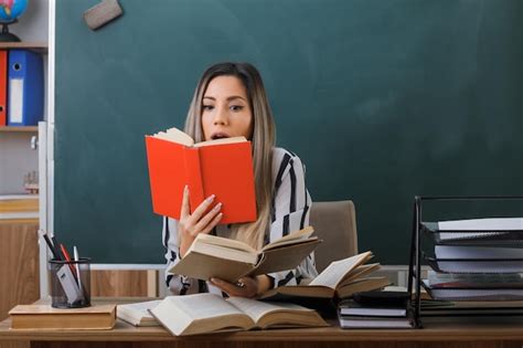 Jeune Femme Enseignante Assise Au Bureau De L école Devant Le Tableau