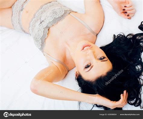 Sexy Beautiful Brunette Woman Lying In Bed In Sensual Gray Lingerie Looking At Camera